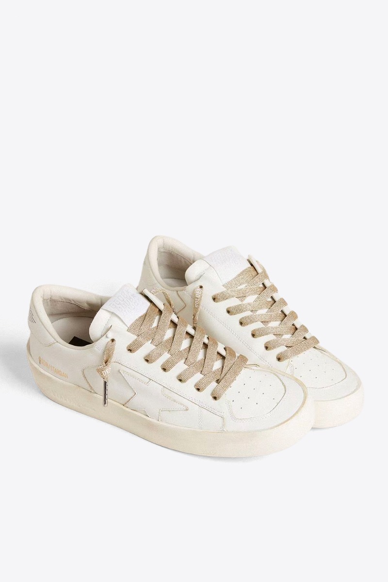 Produit Lacets Golden Goose en lurex doré, logo contrasté blanc. Vue portée avec des sneakers blanches. 
