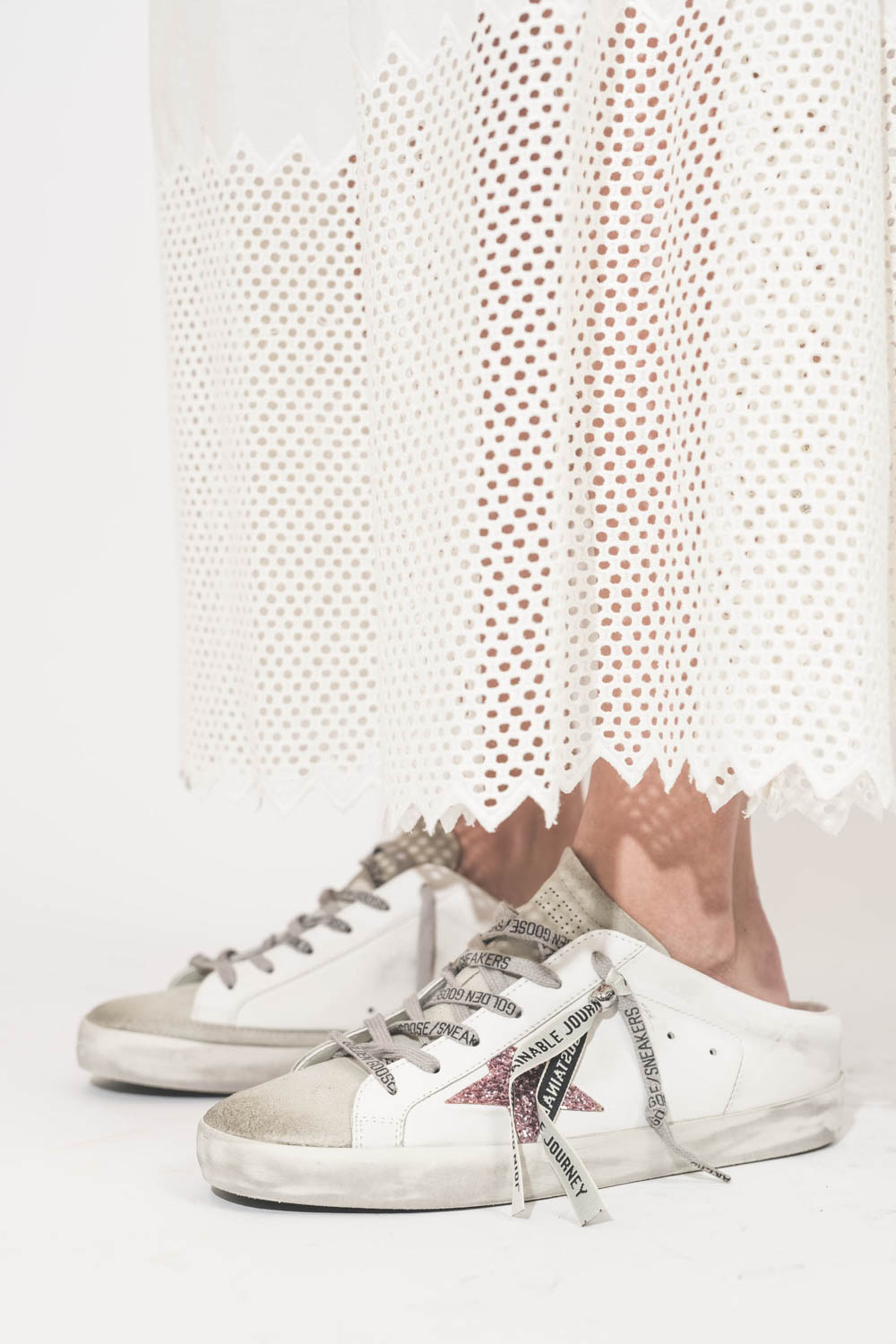 Sneakers Super Star sabot en cuir blanc étoile paillettes rose Golden Goose. Portées avec une jupe longue en coton et nid d'abeille blanc Canary The Great.