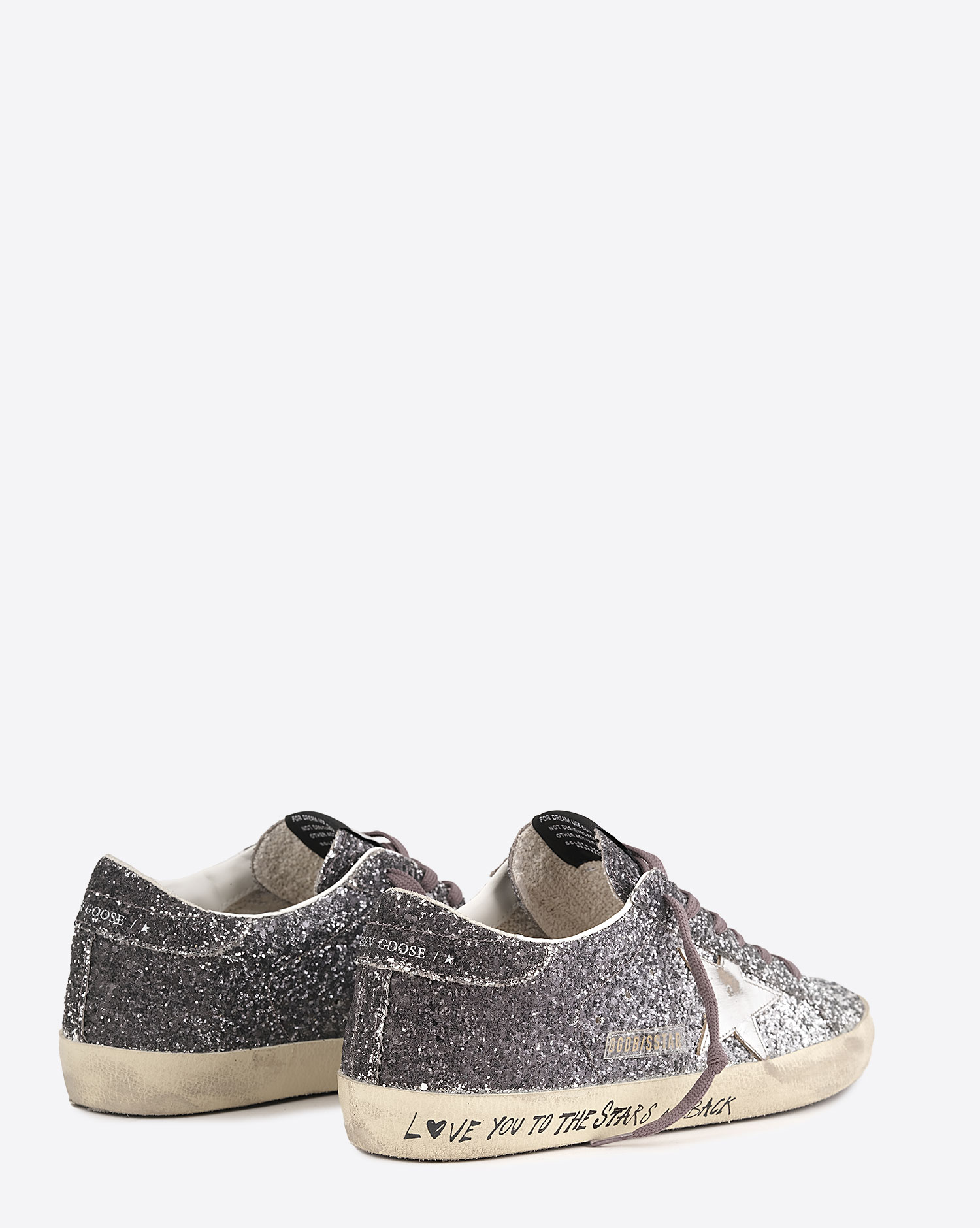 Sneakers entièrement recouvertes de paillettes argentées et noires, étoile en cuir lisse tague écritures noires su la semelle beige "L????VE You To The Star And Back"  Super-star Golden Goose femme. Face.