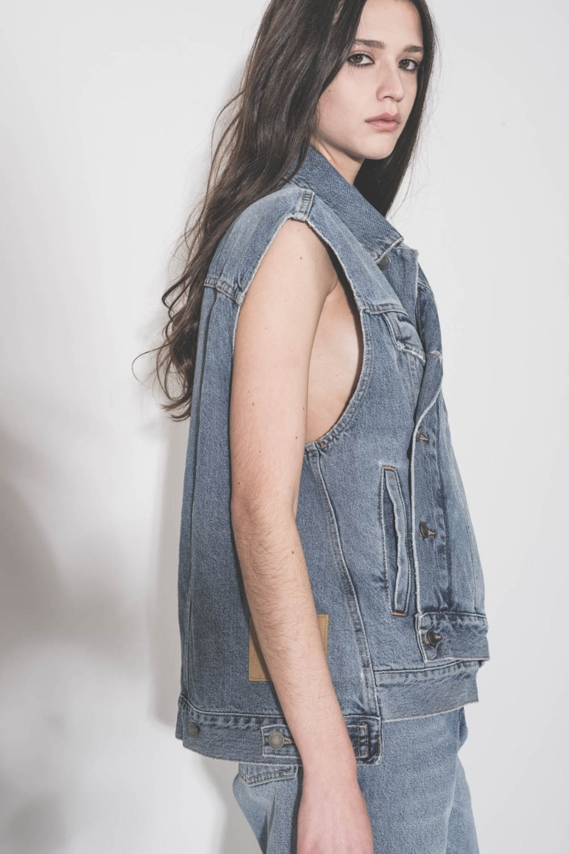 Veste sans manches oversize Janette Haikure en jean bleu d&eacute;lav&eacute; Nordic Blue, port&eacute;e de profil, ferm&eacute;e et crois&eacute;e.