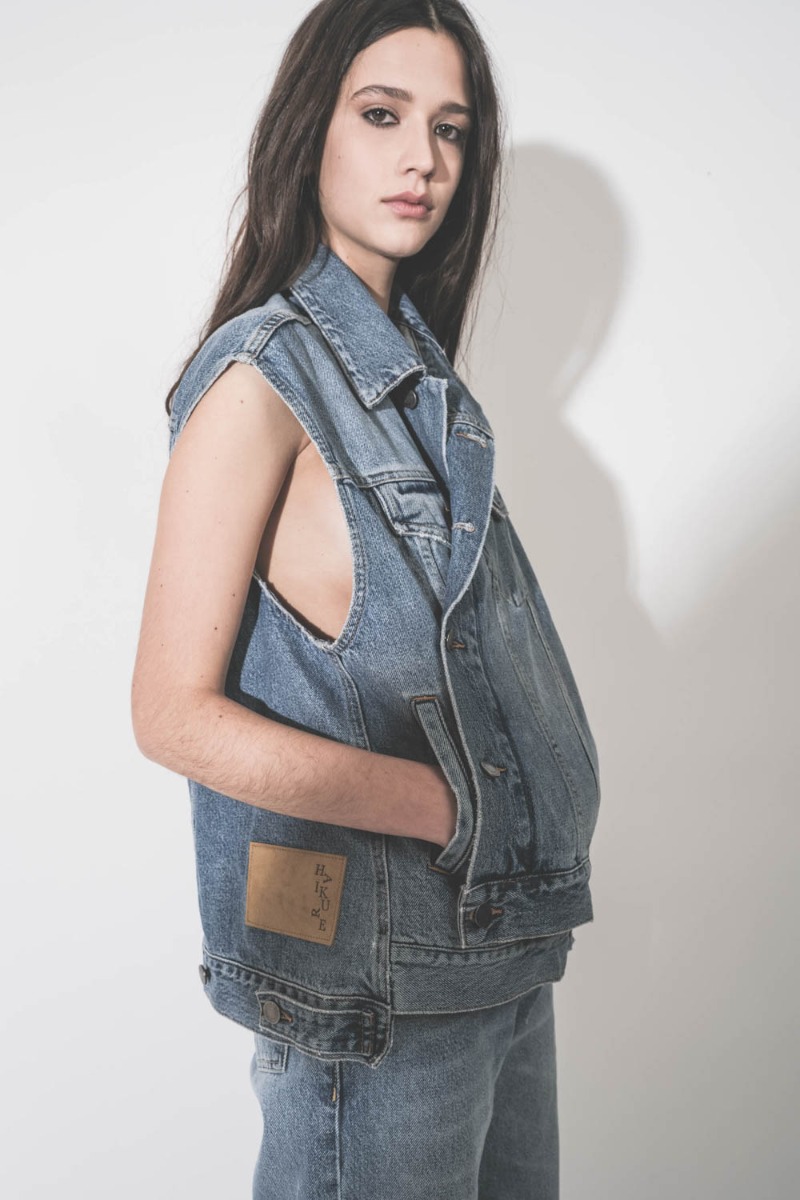 Veste sans manches oversize Janette Haikure en jean bleu d&eacute;lav&eacute; Nordic Blue, port&eacute;e ferm&eacute;e et crois&eacute;e. D&eacute;tail des poches.