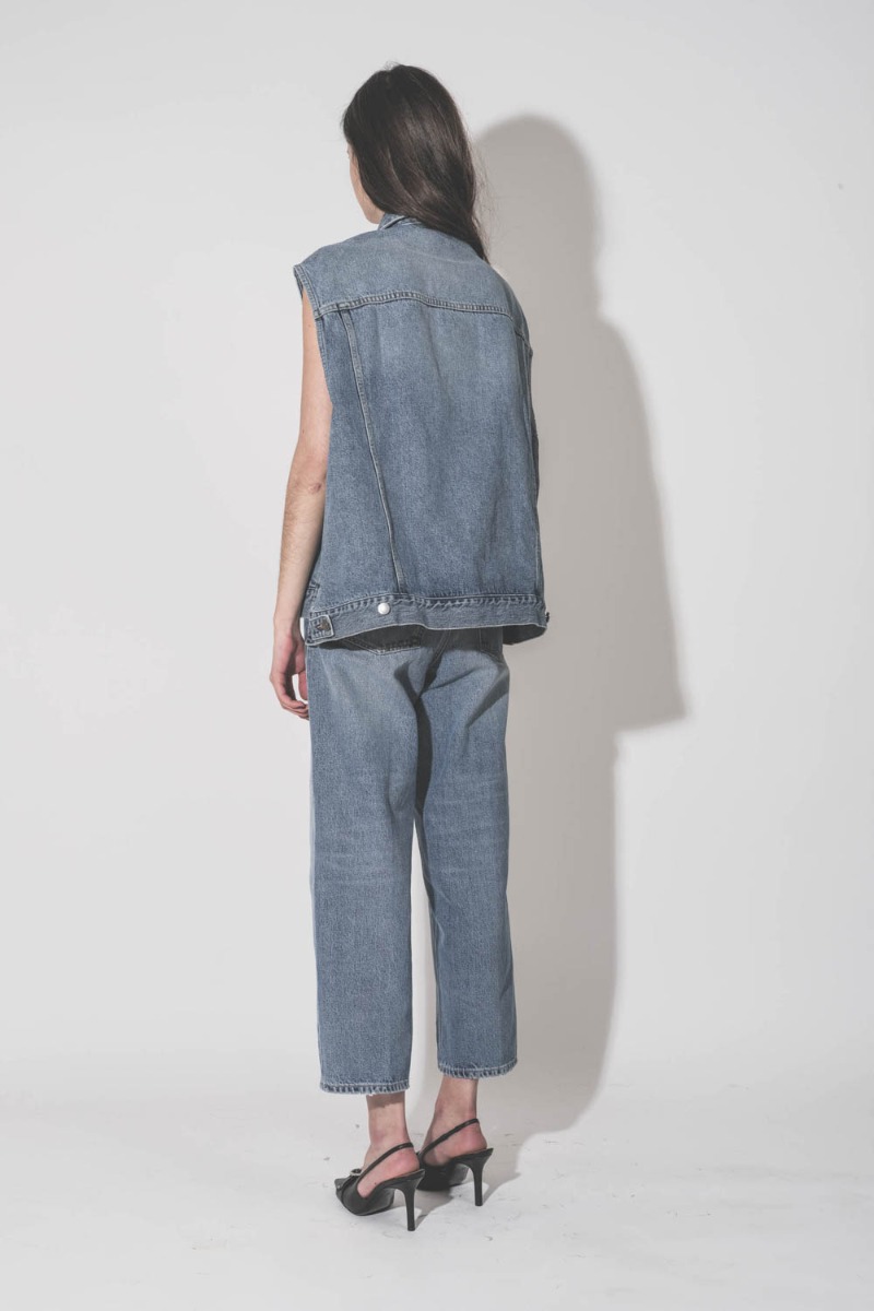 Jean Betty Haikure bleu d&eacute;lav&eacute; Nordic Blue, port&eacute; de dos avec un gilet sans manches Haikure.