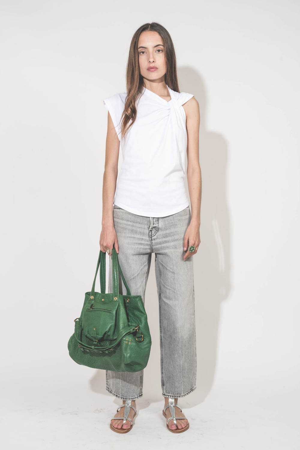 Jean large droit et court délavage Fog gris Betty Haikure. Porté de face avec un tee-shirt blanc Nayda Marant Etoile et des sandales plates en cuir argent Caravelle K.Jacques St-Tropez. Sac cabas en cuir vert gazon Billy M Jérôme Dreyfuss. Bagues en argen