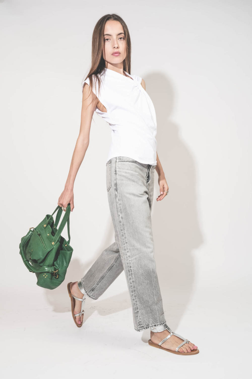 Jean large droit et court délavage Fog gris Betty Haikure. Porté de profil avec un tee-shirt blanc Nayda Marant Etoile et des sandales plates en cuir argent Caravelle K.Jacques St-Tropez. Sac cabas en cuir vert gazon Billy M Jérôme Dreyfuss. Bagues en arg