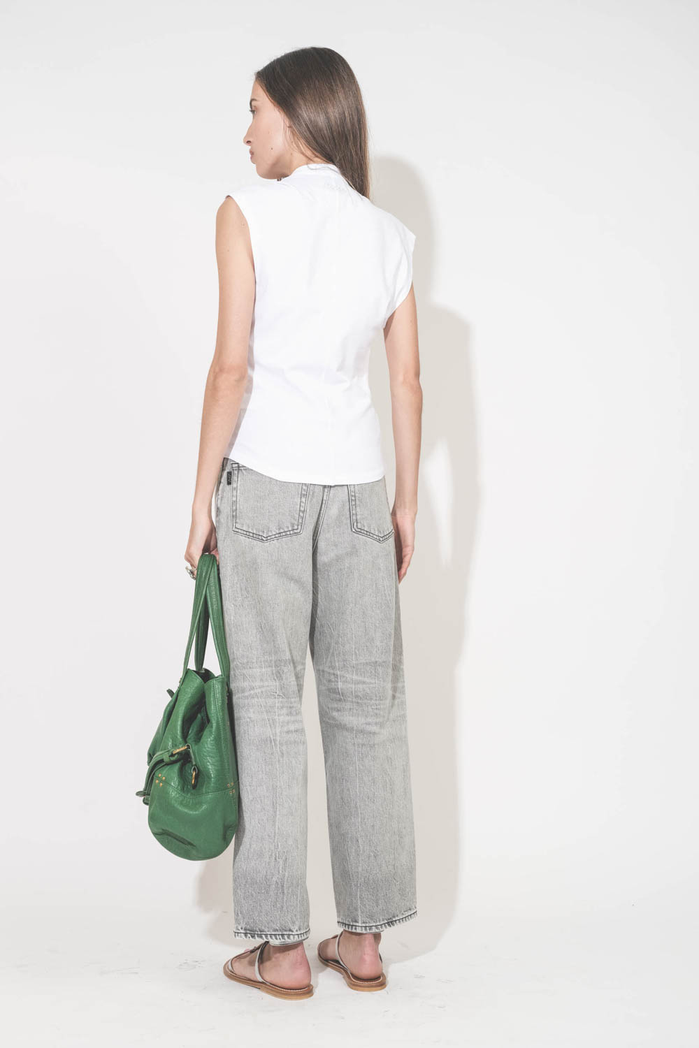 Jean large droit et court délavage Fog gris Betty Haikure. Porté de dos avec un tee-shirt blanc Nayda Marant Etoile et des sandales plates en cuir argent Caravelle K.Jacques St-Tropez. Sac cabas en cuir vert gazon Billy M Jérôme Dreyfuss. Bagues en argent