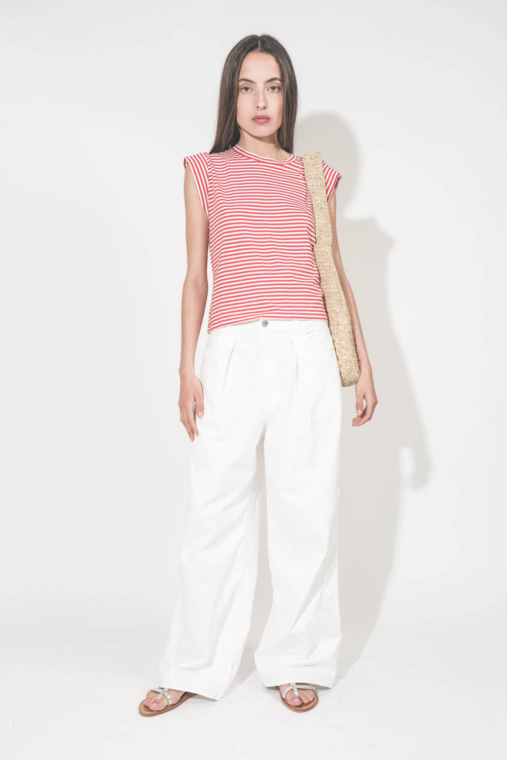 Jean large à pinces taille basse en toile blanche Candy Twill Haikure. Porté de face avec un tee-shirt rayé rouge et blanc The Great. 