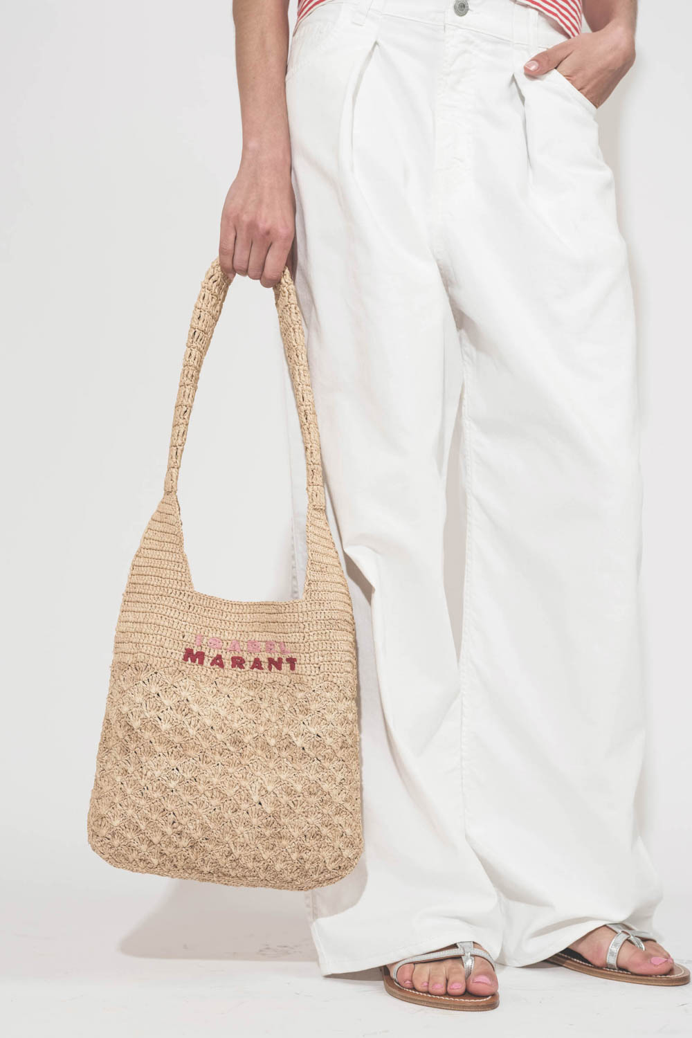 Jean large à pinces taille basse en toile blanche Candy Twill Haikure. Porté de face avec un panier en osier Isabel Marant et des sandales en cuir argent K.Jacques St-Tropez. Détail des pinces.
