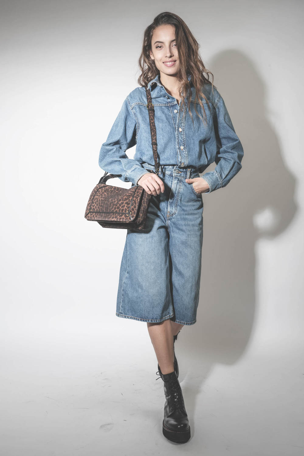 Robe combinaison sous le genoux en jean bleu délavé Méditerranée Tonya Haikure. Porté avec un sac léopard.