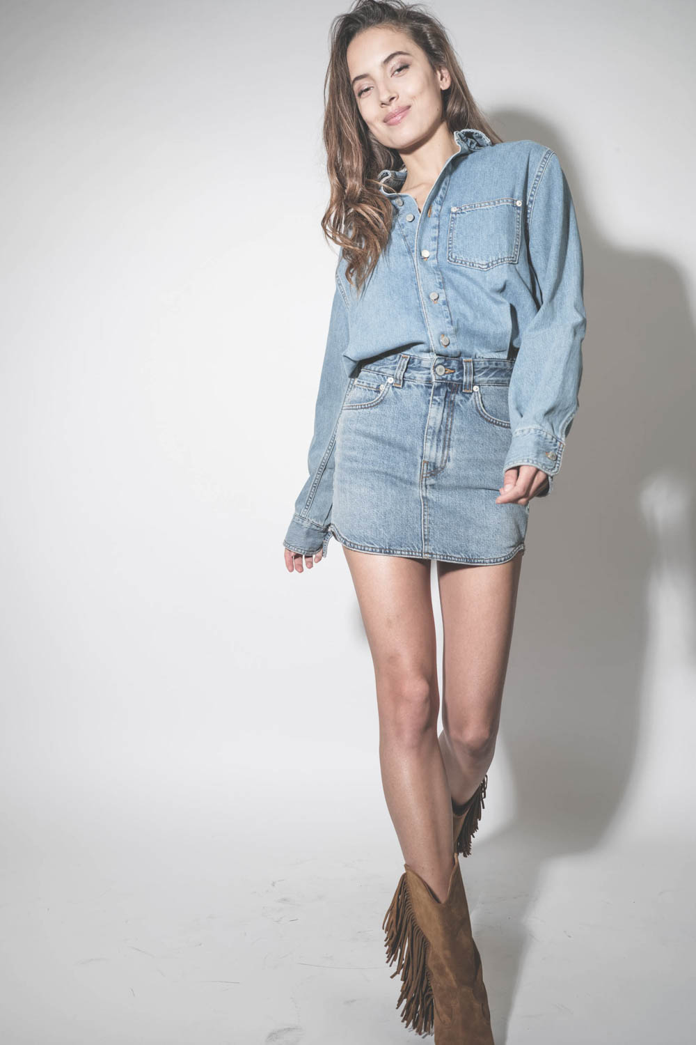 Mini-robe en jean bleu délavé Ionic Blue Tamu Haikure. Porté avec des santiags à franges en cuir suédé marron.