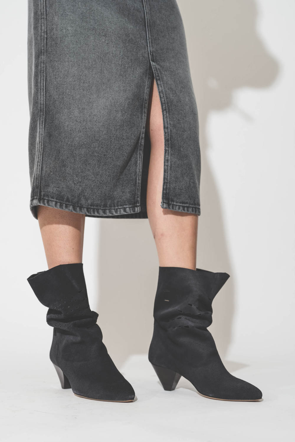 Boots en cuir suédé perforé noir délavé Reachi Isabel Marant. Porté avec une jupe fendue.