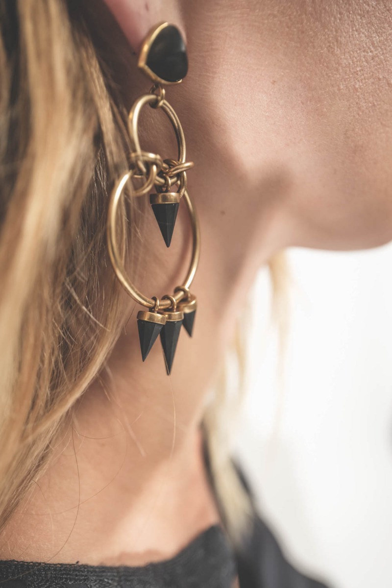 Boucles d'oreilles Be With You Isabel Marant à anneaux et pendentifs en laiton doré et résine noire. Portées de profil.