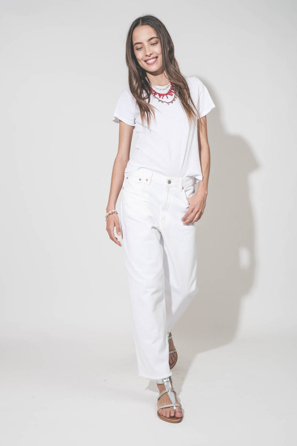 Collier pierres rouges et pampilles en métal argentés Isabel Marant. Porté en accumulation avec un collier coquillage Noki et un collier perles et os rouge Isabel Marant. Tee-shirt blanc Little The Great, jean blanc Georgia Denimist et sandales en cuir ar