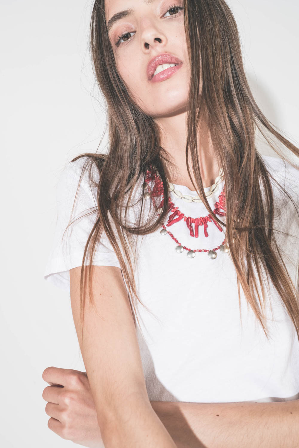 Collier de perles et os rouges Jolana Isabel Marant. Porté de face en accumulation avec un collier coquillage Noki et un collier Adriel en perles rouges et pampilles en métal argenté Isabel Marant. 