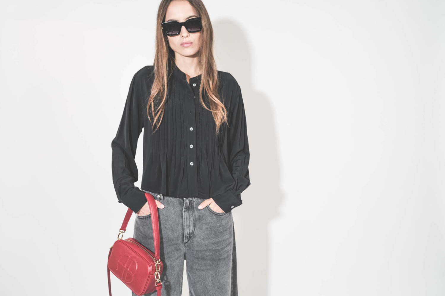 Chemise courte manches longue col Mao plis devant en viscose noire Adzara Marant Etoile. Porté avec un jean large fluide gris clair Joanny Marant Etoile. Sac en cuir rouge logo AB Lili Anine Bing et lunettes de soleil montures noires Indio AB Anine Bing.
