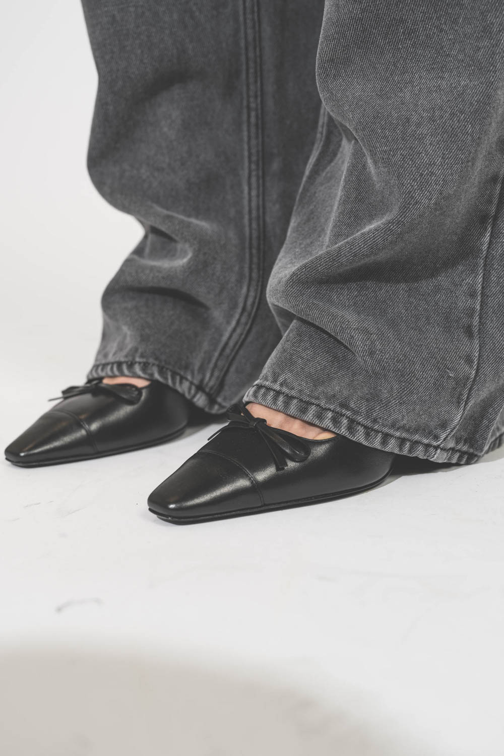Jean large et fluide en Lyocell et coton gris clair Joanny Marant Etoile. Porté avec des escarpins à talons en cuir noir Slingbacks Freya Anine Bing. Détail de l'ourlet piqué. 