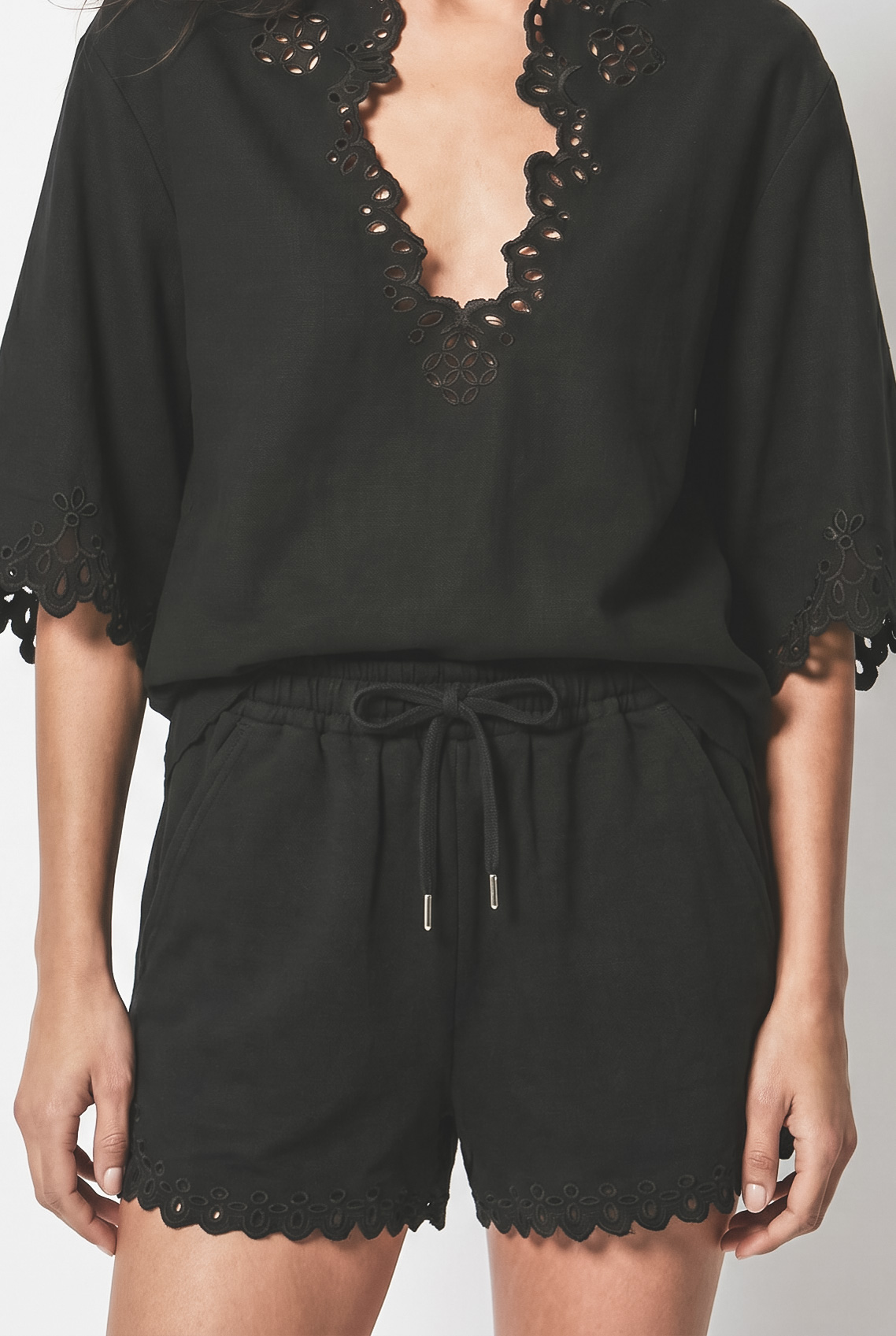 Short Balyme Isabel Marant Étoile en coton noir à broderies anglaises ajourées porté avec la blouse Balyme assortie. Détail du lien de serrage à la taille. 