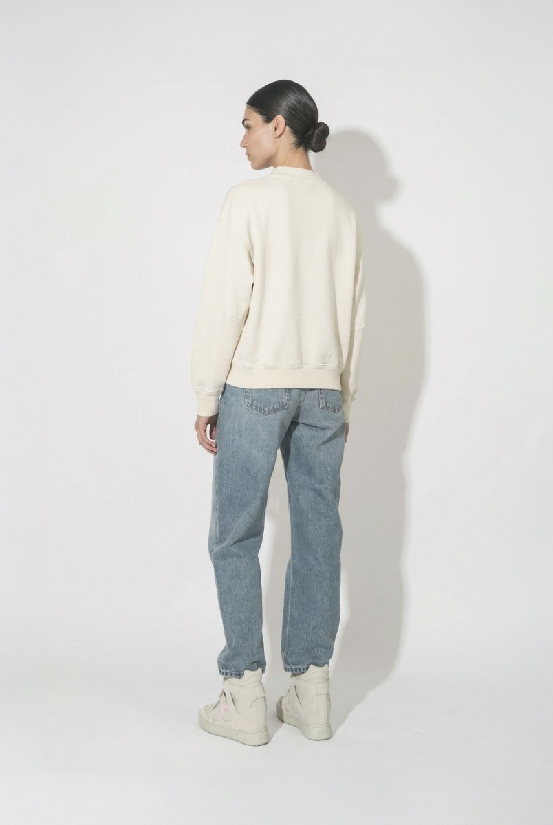 Sweatshirt Moby Isabel Marant &eacute;toile en coton &eacute;cru et logo rose sur le devant, port&eacute; de dos avec un jean bleu Fritz Anine Bing. 