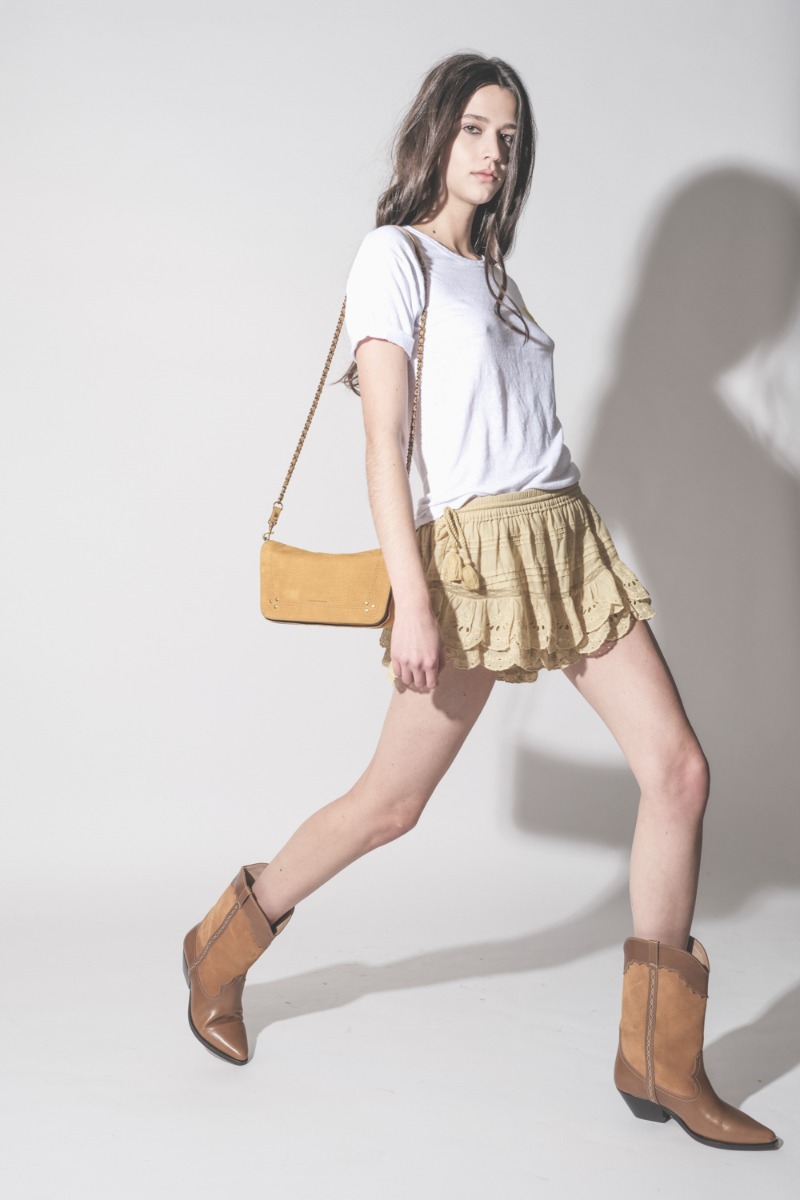 T-shirt Koldia Isabel Marant &Eacute;toile en lin blanc, logo jaune flock&eacute; au-dessus de la poitrine, port&eacute; de profil avec un short en dentelle Isabel Marant &Eacute;toile.