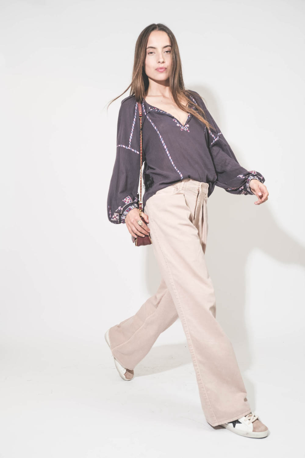 Top manches longues en voile de coton brodé bleu nuit lilas Fernanda Isabel Marant Etoile. Porté de profil avec un jean large à pinces en coton rose poudré Candy Twill 45 Haikure. Sneakers en cuir blanc languette rose Super Star 12170 Golden Goose et sac 