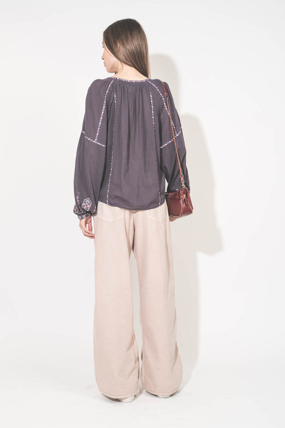 Top manches longues en voile de coton brodé bleu nuit lilas Fernanda Isabel Marant Etoile. Porté de dos avec un jean large à pinces en coton rose poudré Candy Twill 45 Haikure. Sneakers en cuir blanc languette rose Super Star 12170 Golden Goose et sac Bob