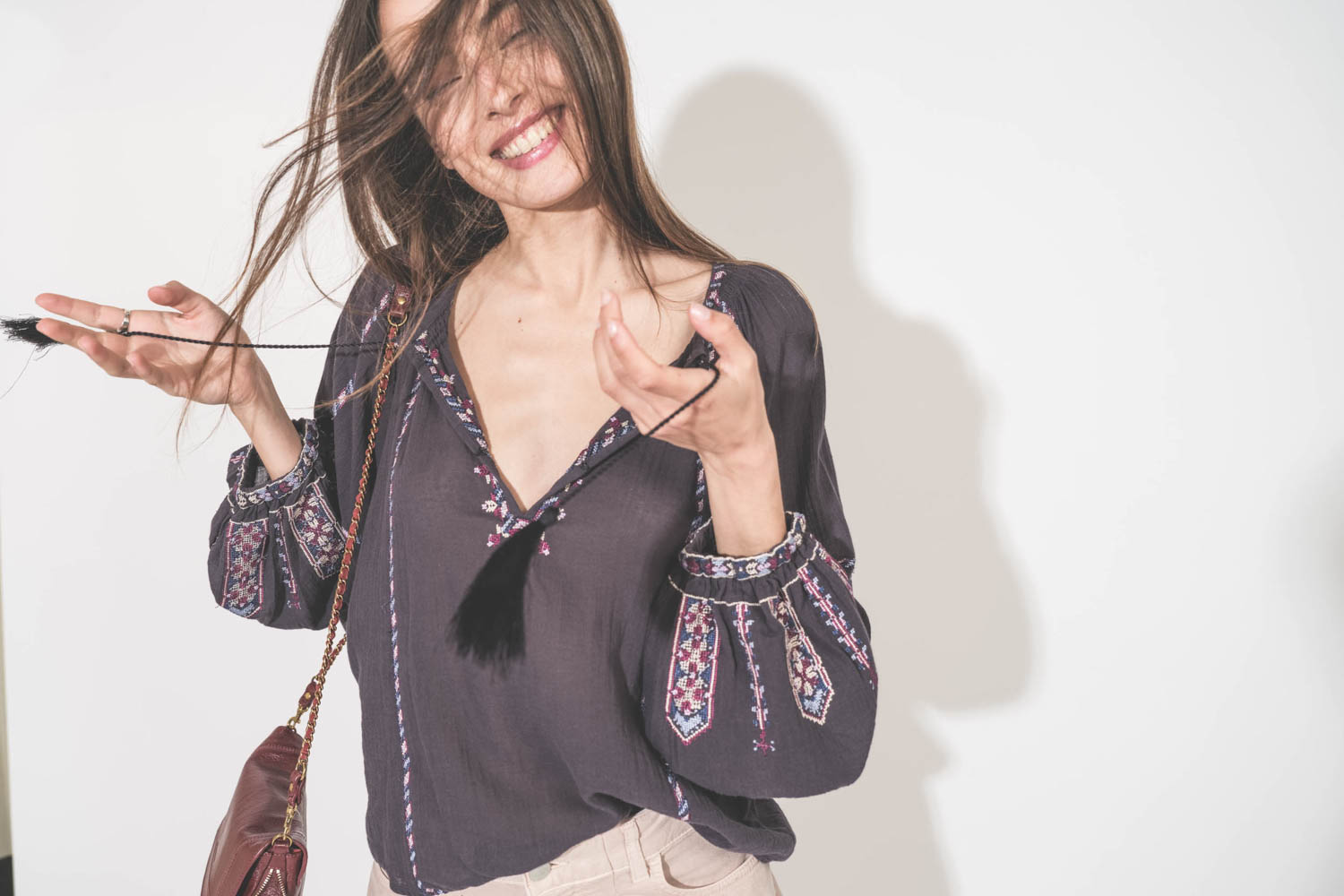 Top manches longues en voile de coton brodé bleu nuit lilas Fernanda Isabel Marant Etoile. Porté avec un jean large à pinces en coton rose poudré Candy Twill 45 Haikure. Sac Bobi S en cuir acajou Jérôme Dreyfuss. 