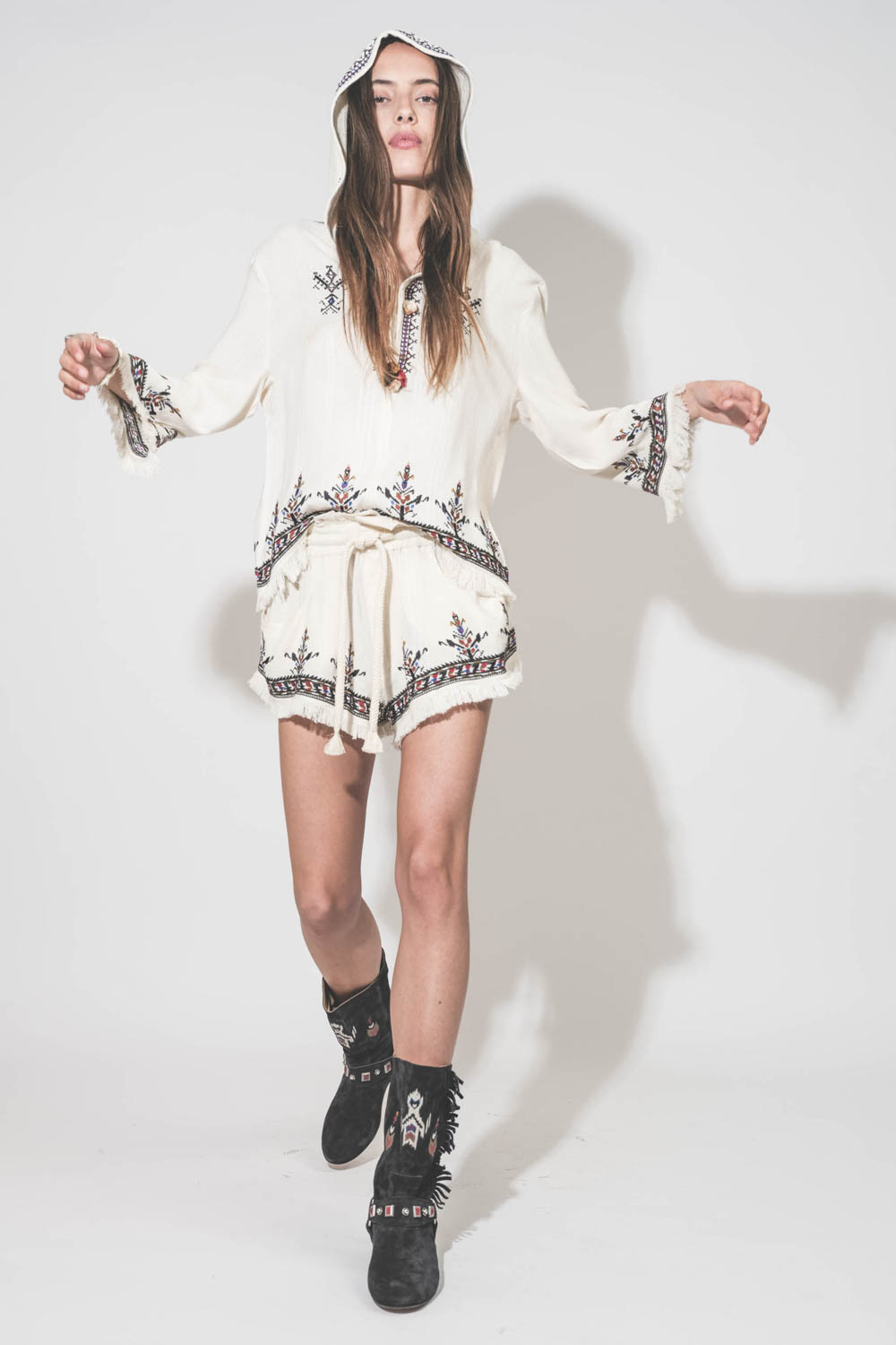 Top manches 3/4 finition franges à capuche écru avec broderies et pompons Kameya Marant Etoile. Porté de face avec le short Kriss assorti Marant Etoile et des bottes en cuir suédé noir brodé Siani Isabel Marant.