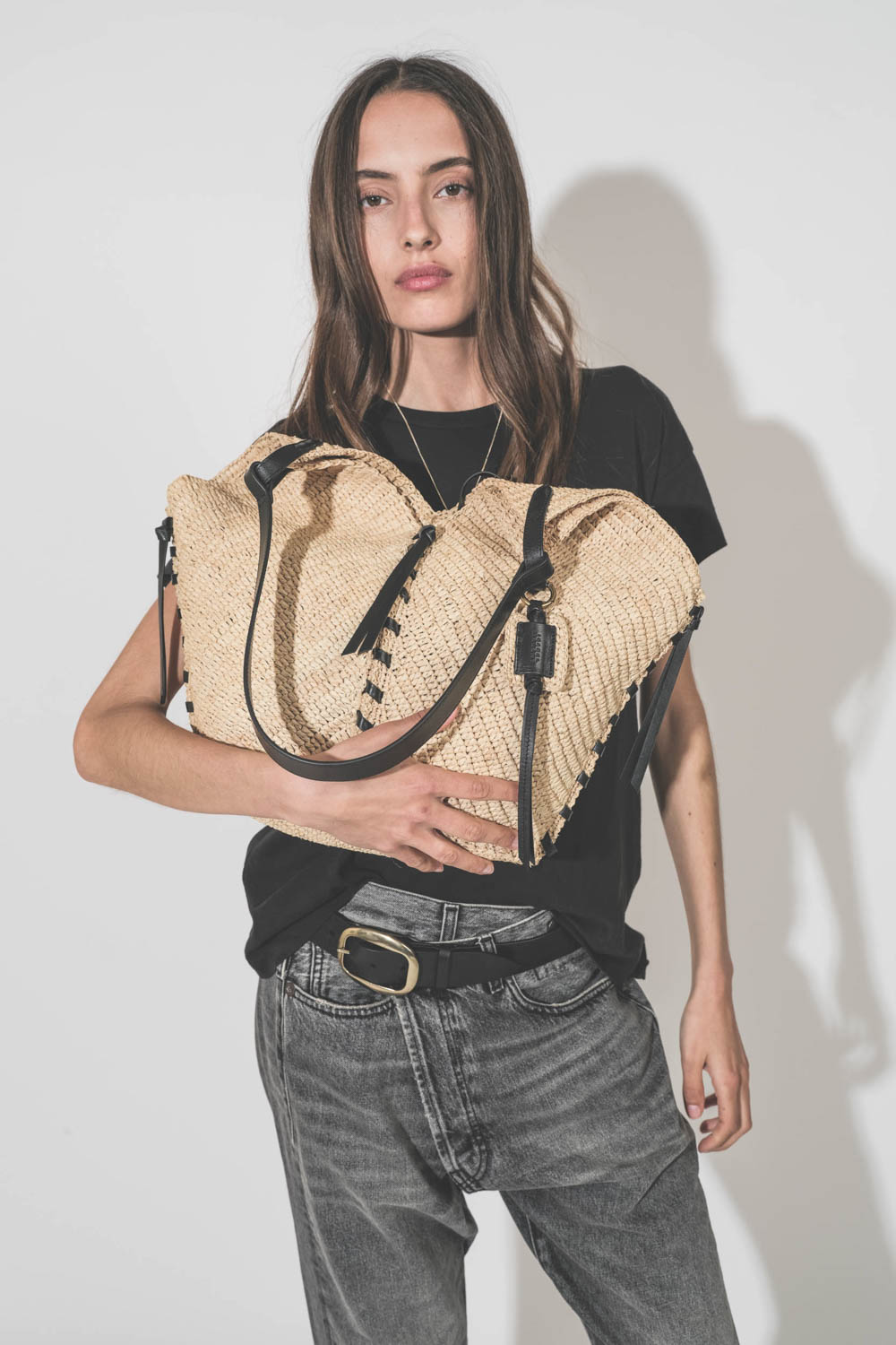 Panier en osier naturel finition cuir noir porté main ou épaule grand modèle Tampa Isabel Marant. Porté dans les bras avec un tee-shirt noir Boxy Crew The Great et un jean Crossover Leyton Black R13 Denim. Ceinture Dara Isabel Marant.