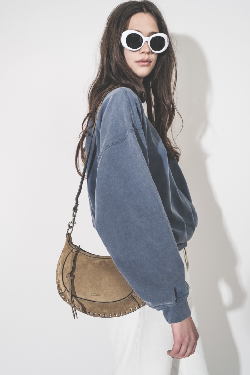 Sac Oskan Moon Isabel Marant en cuir suédé taupe clous argent, porté de profil, bandoulière longue à l'épaule.