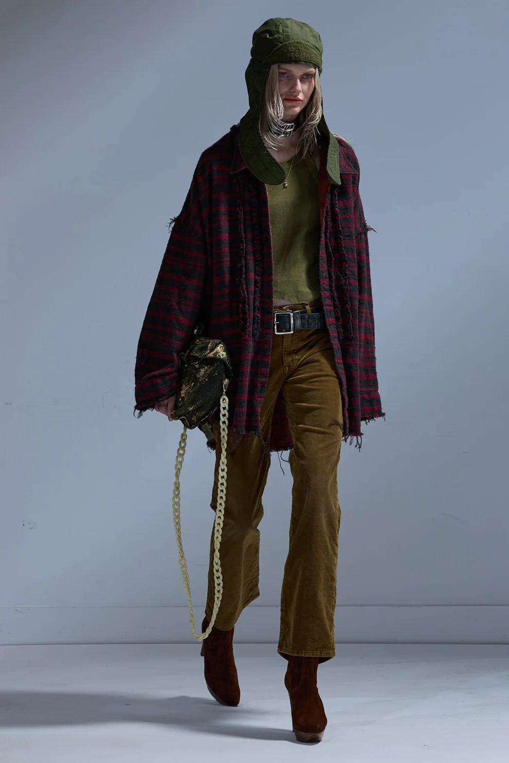 Jean taille basse évasé Joan Kick Flare R13 en velours de coton côtélé marron, porté de face avec un manteau à carreaux rouge.