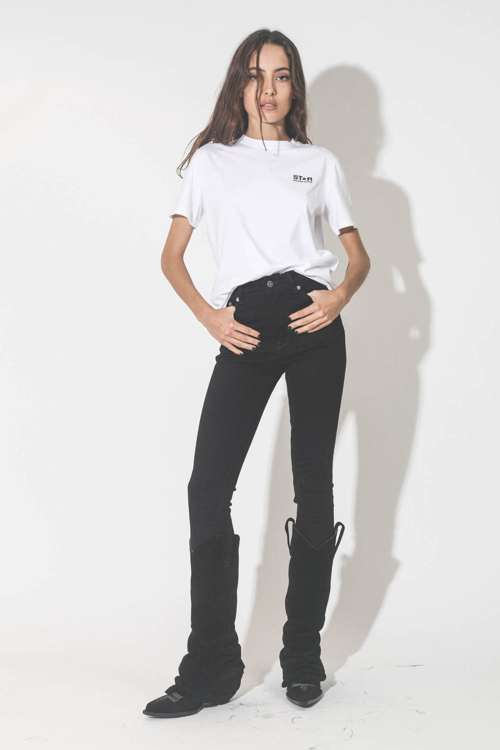 Jeans skinny taille haute en toile noir Deena Golden Goose. Porté avec des bottes santiags noires.