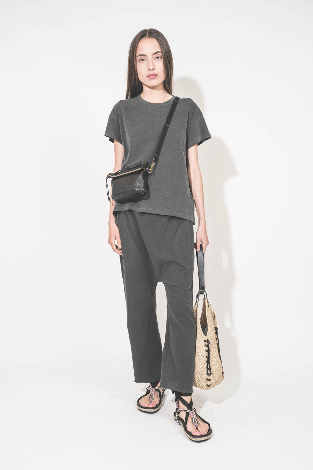 Bandoulière sangle et cuir noir finition laiton doré réglable avec une boucle esprit ceinture Jérôme Dreyfuss. Porté avec une pochette Lucky en cuir chèvre noir grainé Jérôme Dreyfuss. Tee-shirt manches courtes et pantalon sarouel en jersey noir délavé. S