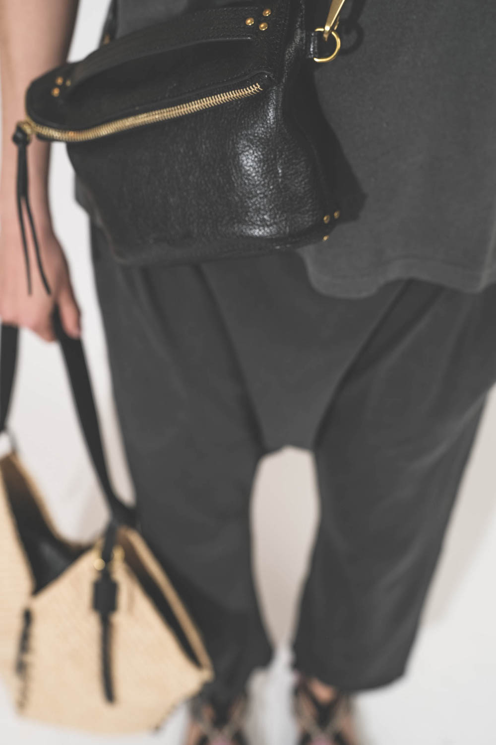 Pochette en cuir de chèvre noir grainé portée crossbody avec une bandoulière sangle large noire Jérôme Dreyfuss. Tee-shirt manches courtes Boxy Crew et pantalon sarouel en jersey noir délavé The Great. Sandales en cordes tressées et ruban noir Gypsa Isabe