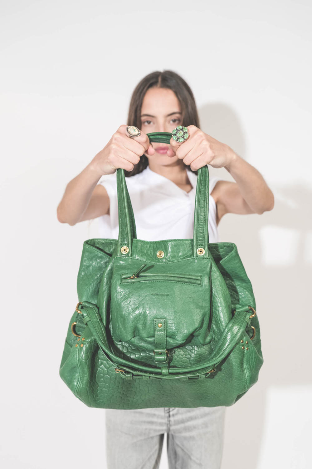 Sac forme cabas en cuir vert gazon Billy M Jérôme Dreyfuss. Porté de face avec deux bagues Harpo en argent et turquoise.