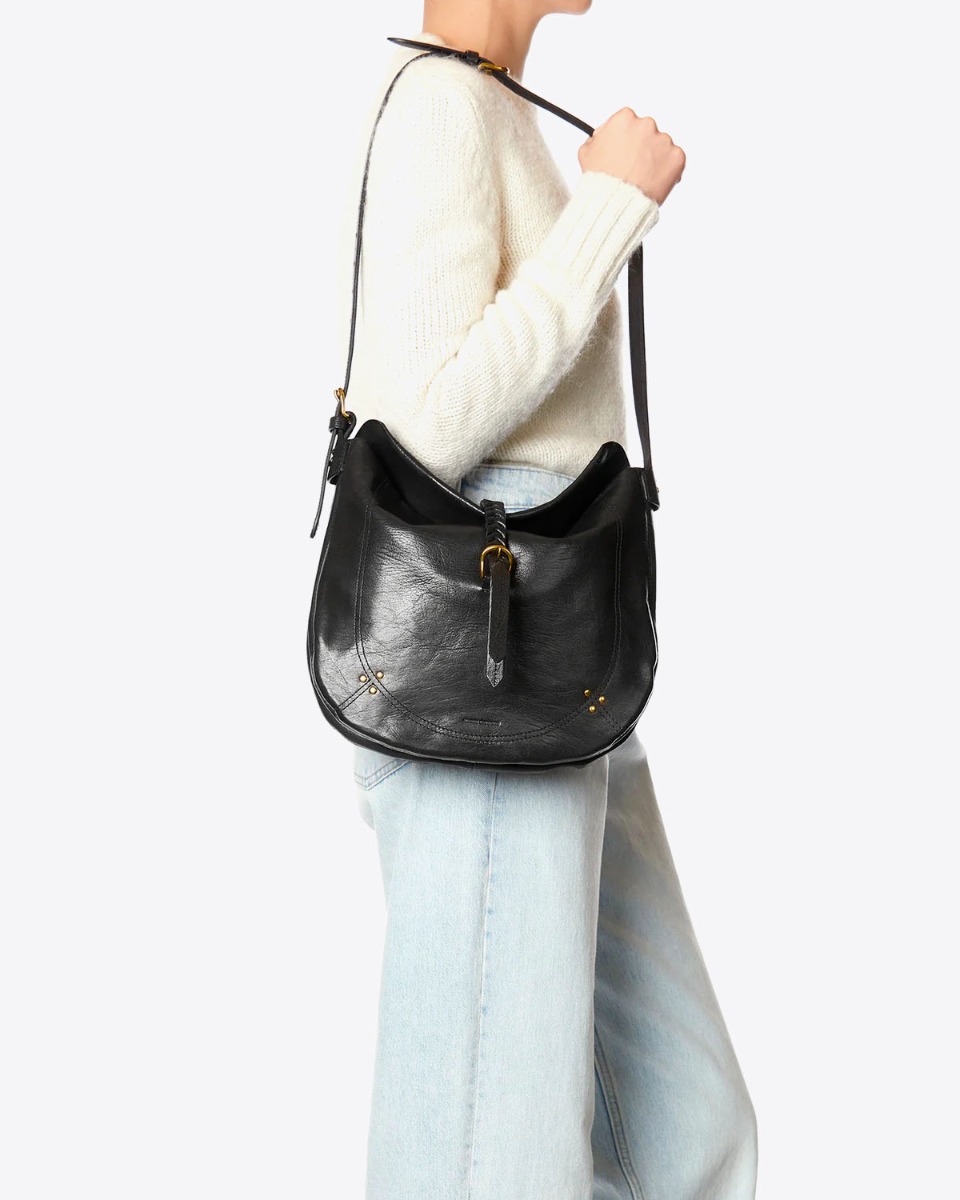 Sac besace Luis Jérôme Dreyfuss en cuir de chèvre noir grainé porté à l'épaule.