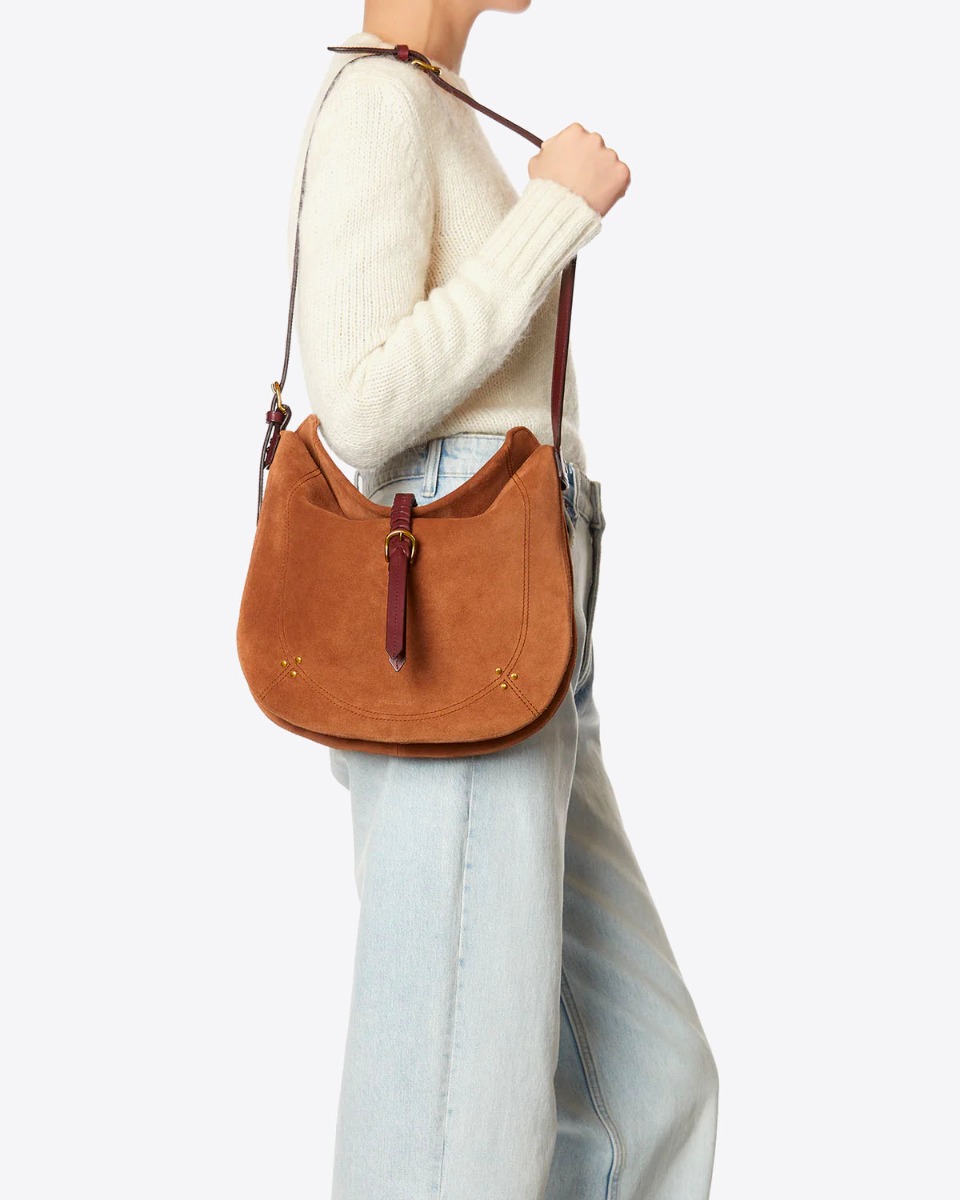 Sac besace Luis Jérôme Dreyfuss en cuir suédé caramel porté à l'épaule.