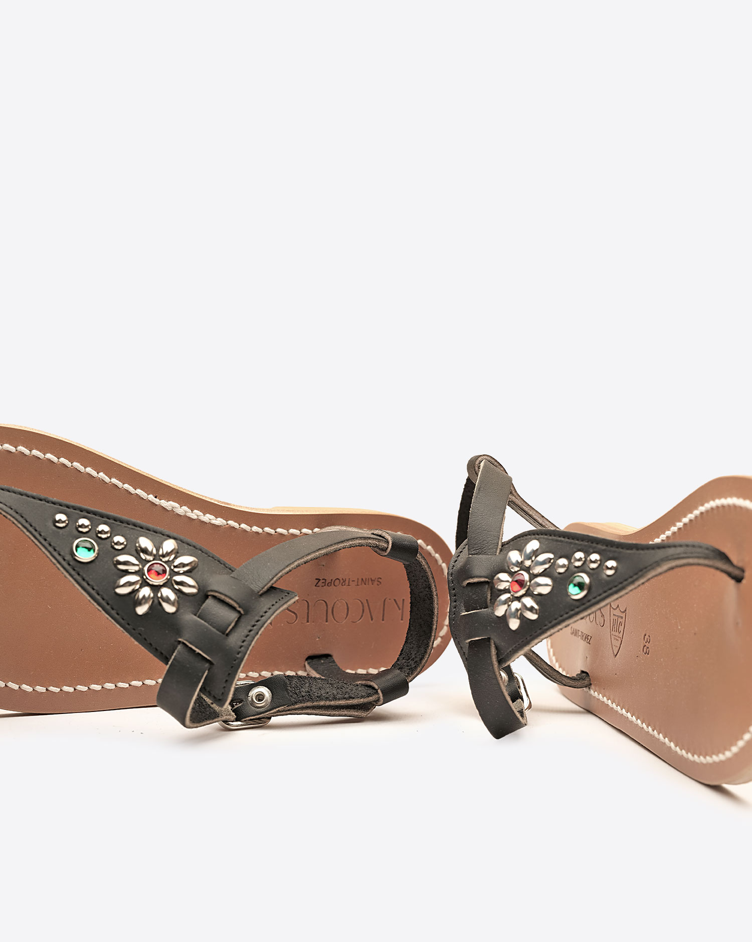 Sandales Coriolan K.Jacques x HTC en cuir noir, ornées de clous métalliques argentés et de pierres colorées formant une fleur, fabrication artisanale française. Détail de la customisation.