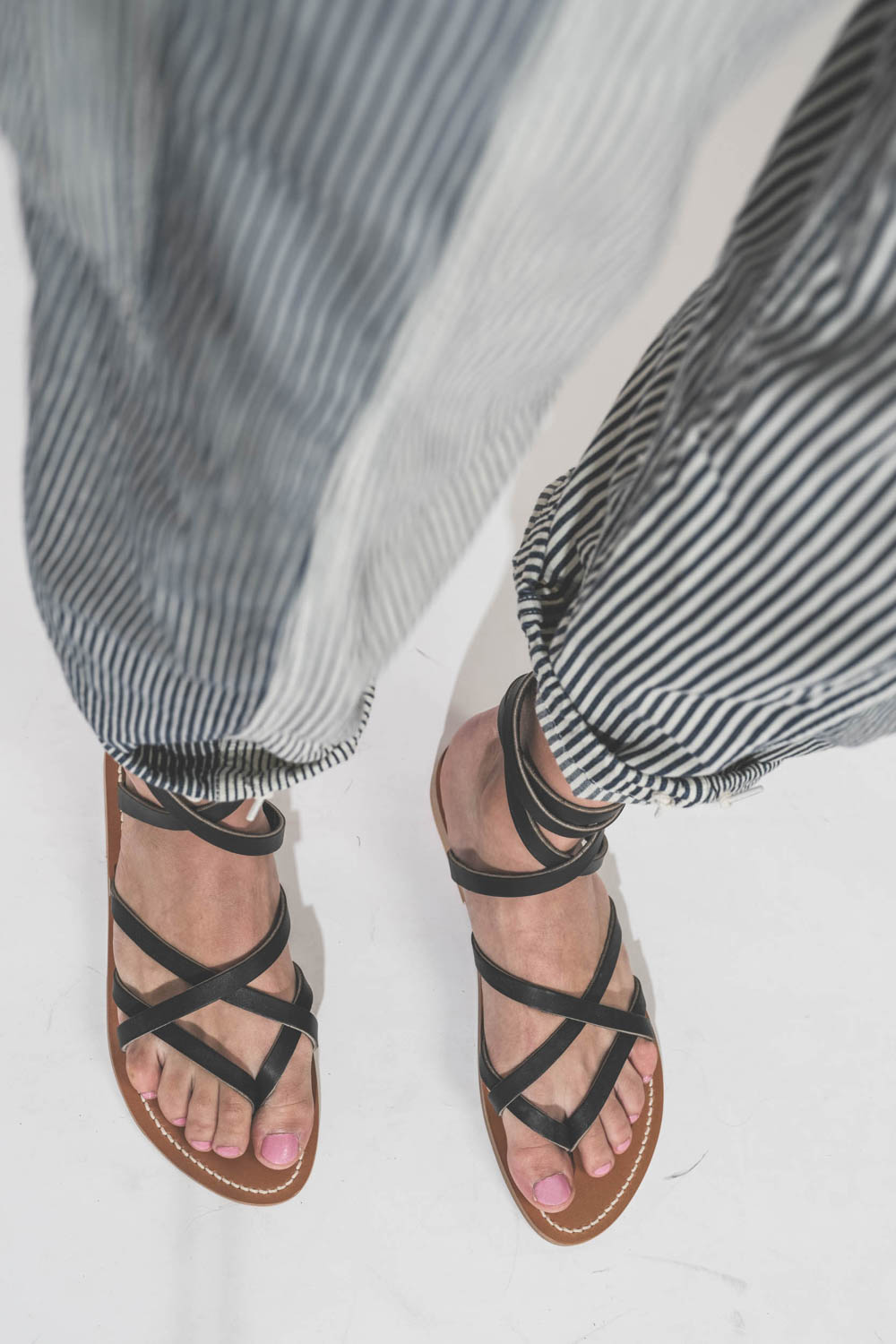 Sandales plates en cuir noir Zenobie K.Jacques Saint-Tropez. Porté avec un pantalon à rayures Cargo Railroad R13 denim.