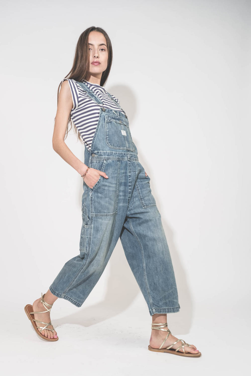 Sandales en cuir doré Metyl Champan Zenobie K.Jacques St-Tropez. Porté avec un tee-shirt manches raccourcies bleu et blanc vintage Peak Shoulder The Great et une salopette en jean bleu ciel relaxed Overal Holton Indigo Denimist. Bracelet 3 tours Tibétain 