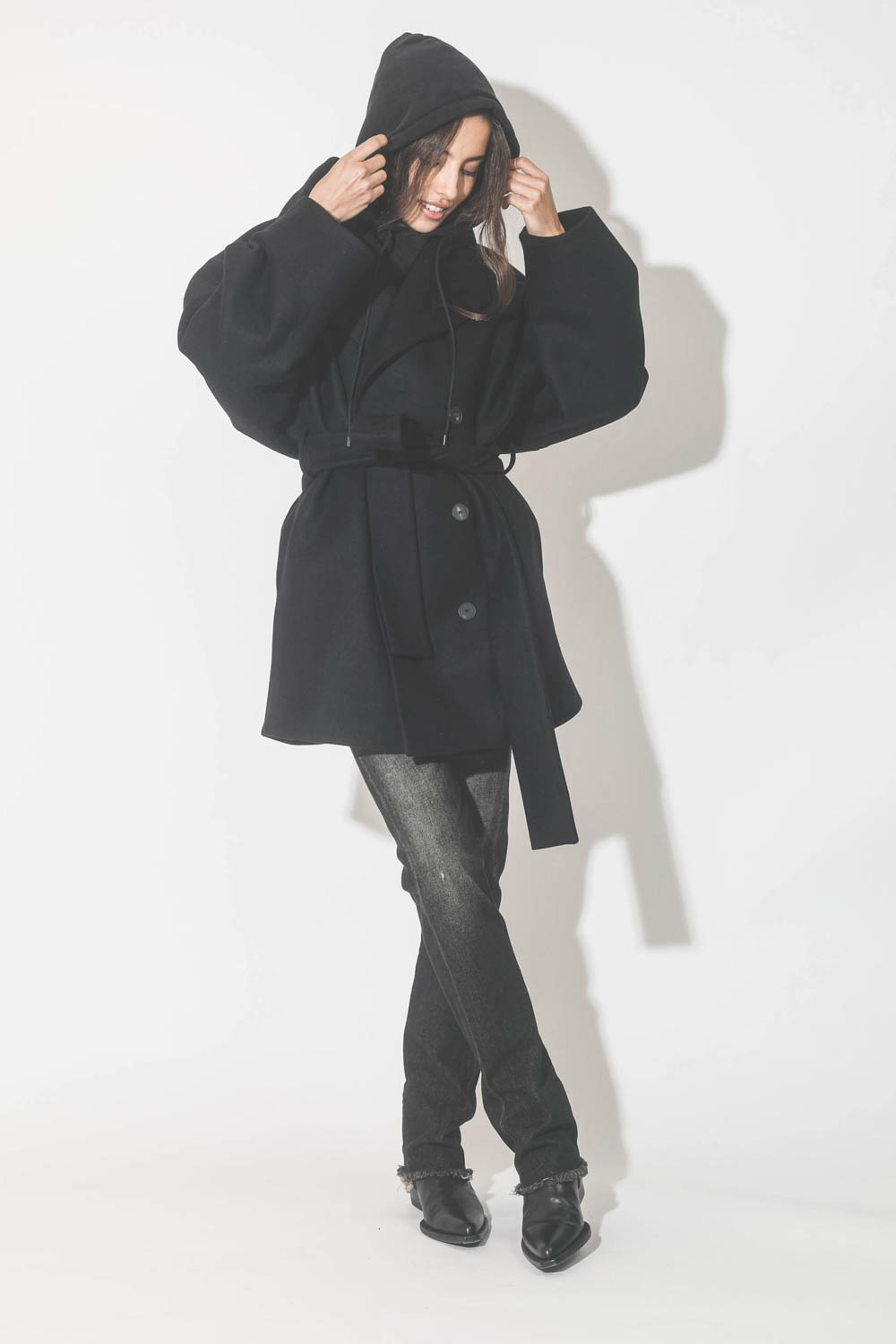 Manteau caban ceinturé en drap de laine noir Suzzane Vautrait. Porté avec des boots santiags.