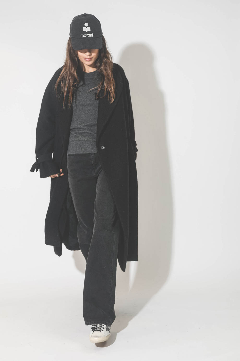 Manteau souple en laine noir Maison Flaneur. Port&eacute; avec une casquette.