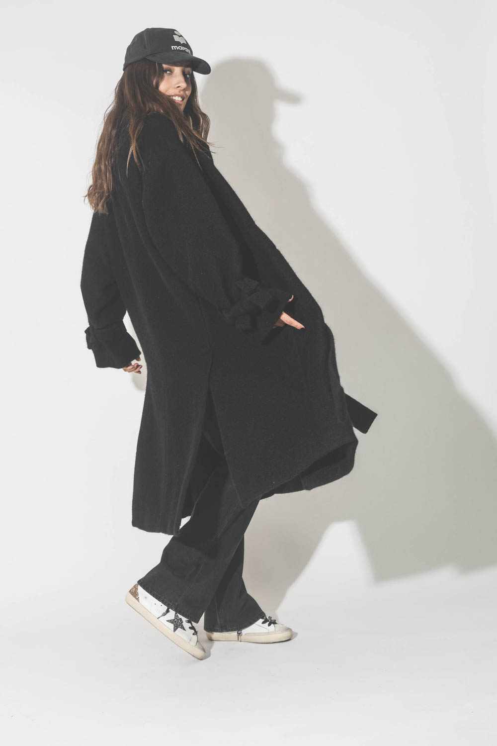 Manteau souple en laine noir Maison Flaneur. Port&eacute; avec des baskets.