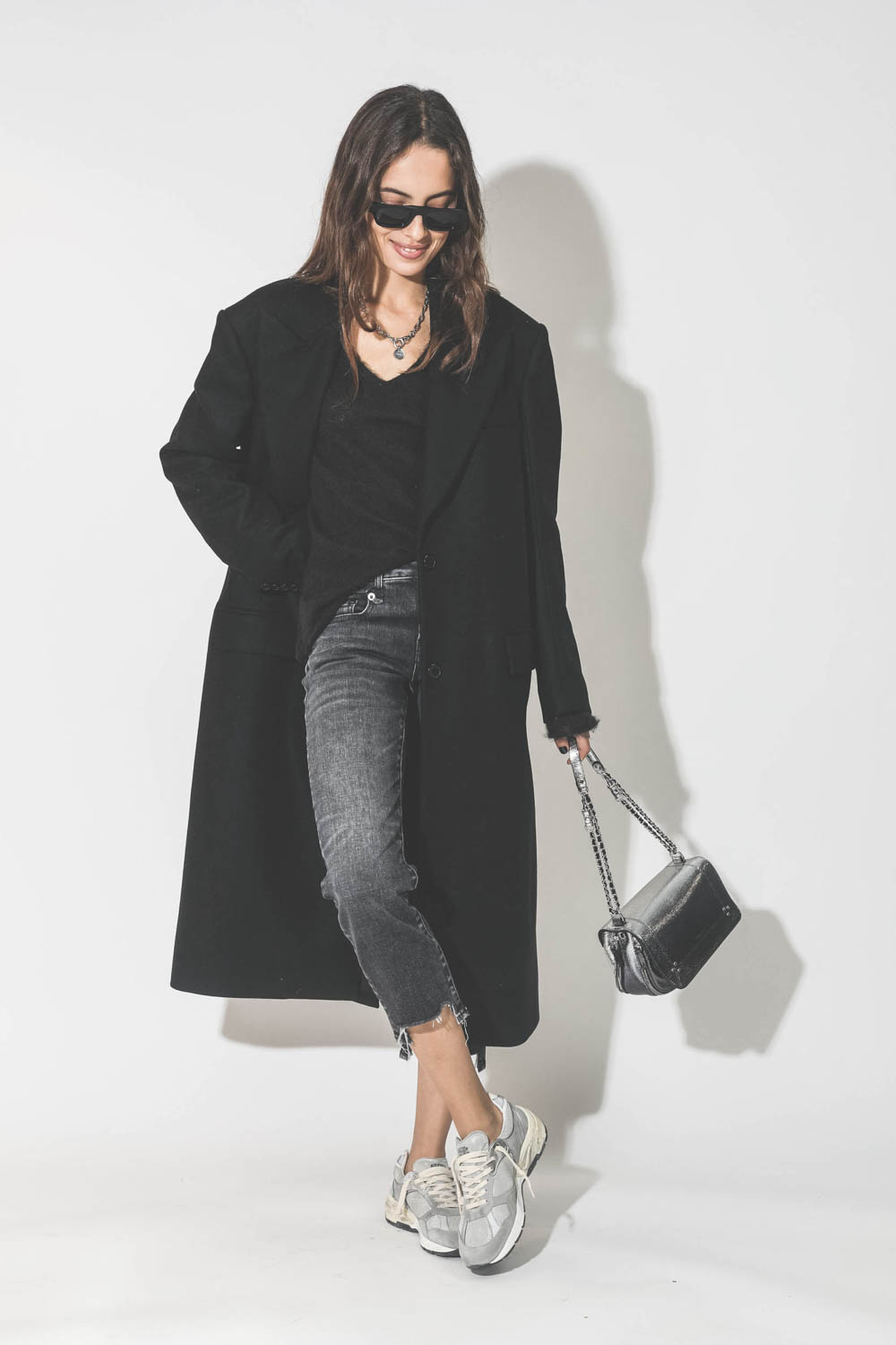 Manteau long en drap de laine noir Maison Flaneur. Porté avec un jeans court et des sneakers.