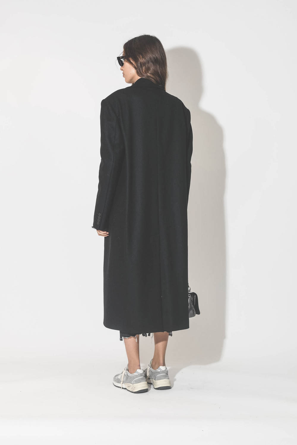 Manteau long en drap de laine noir Maison Flaneur. Porté de dos. 