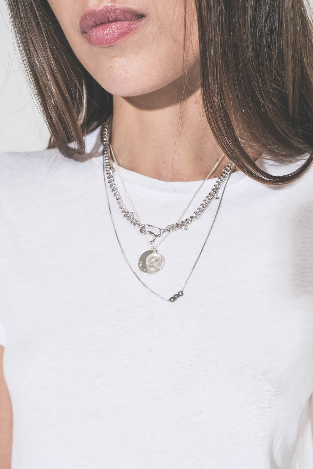 Produit Collier long chaine avec lettre Dad en argent Maria Black. Porté en accumulation avec un collier chaine Berline en argent et un collier L'amour en argent Pascale Monvoisin. Tee-shirt blanc col rend The Great. 