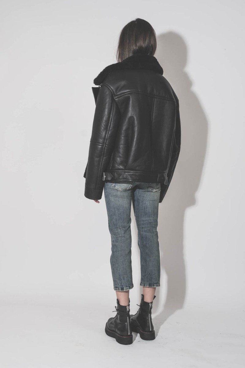 Blouson bombardier Mikuta en cuir et peau de mouton noir ultra-chaude, port&eacute; de dos avec un jean bleu R13.