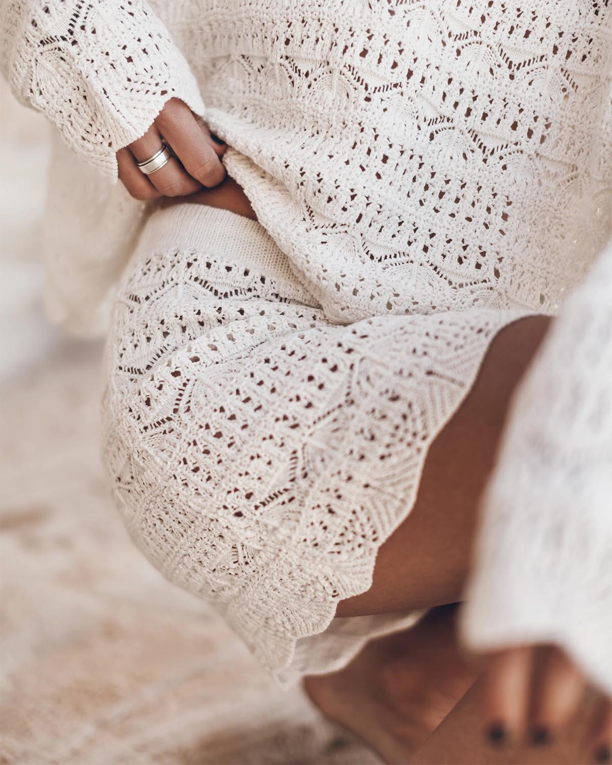 Mini-jupe en crochet écru en lin et coton Mikuta. Portée de face avec un pull oversize en crochet écru assorti. 