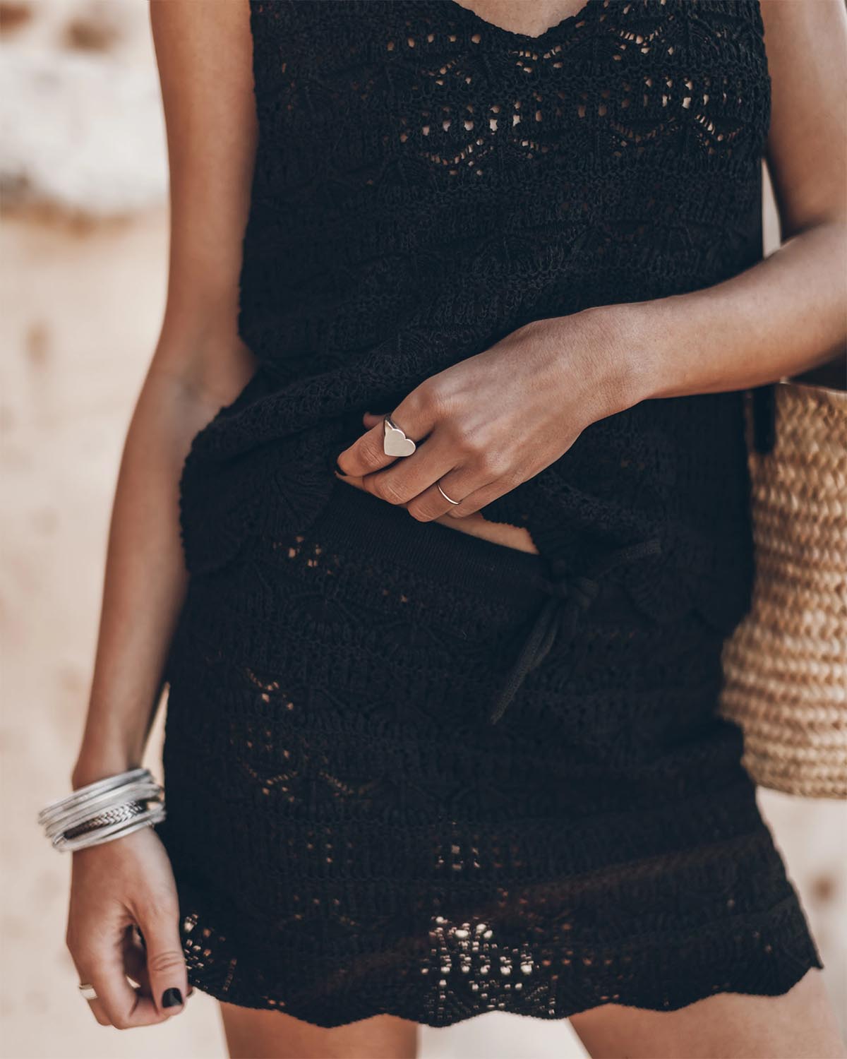 Mini-jupe en crochet noir en lin et coton Mikuta. Porté de face avec un débardeur en crochet noir assorti. Bague coeur en argent Mikuta.
