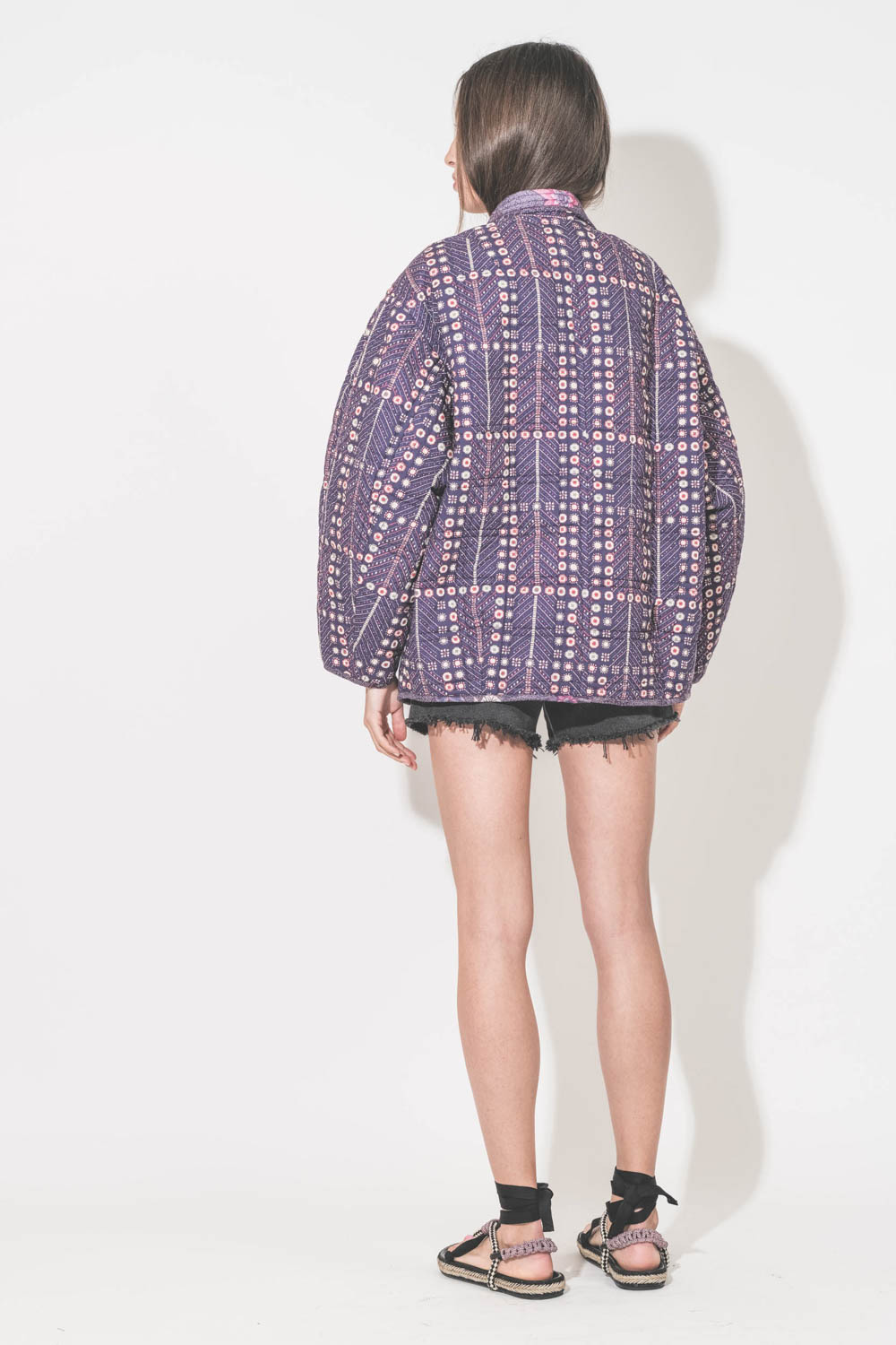 Short taille haute en jean noir Mikuta. Porté de dos avec un tee-shirt Boxy Crew écru The Great, une veste Chancel Marant Etoile et des sandales Gypsa noir Isabel Marant.