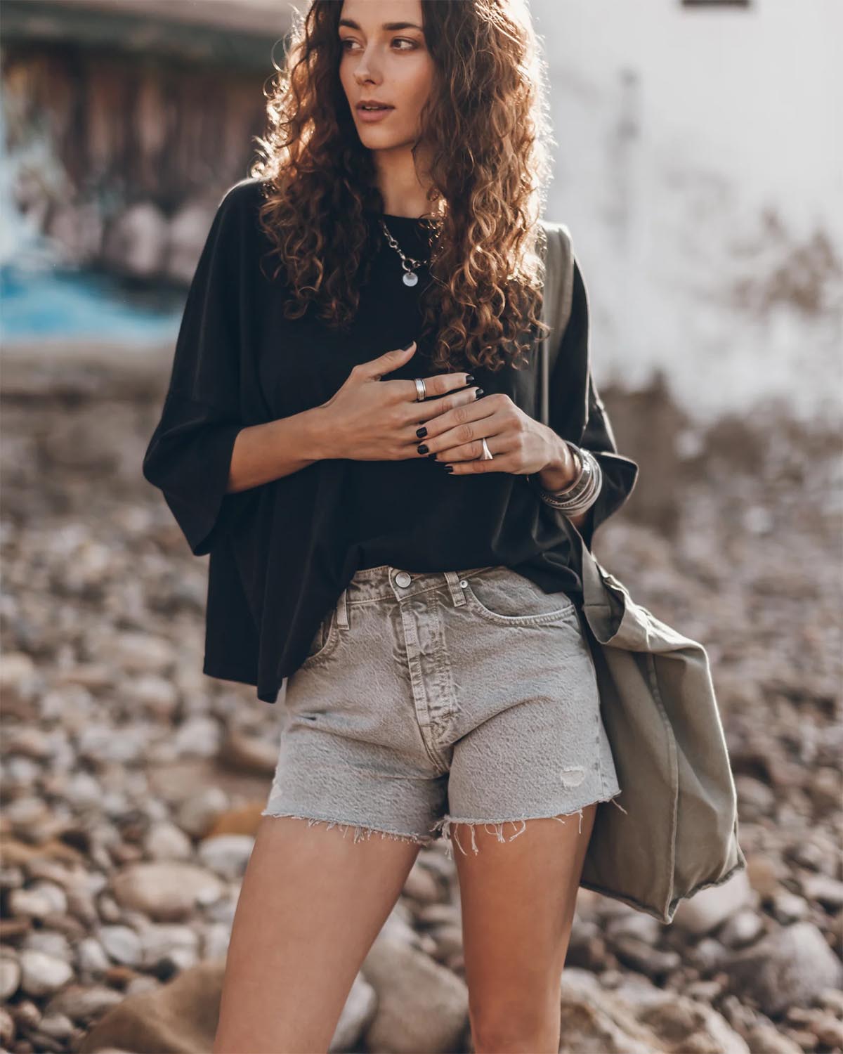 Produit Tee-shirt manches courte épaule basse en coton noir oversize Mikuta. Porté avec un short en jean kaki Mikuta et des bijoux en argent Mikuta.  