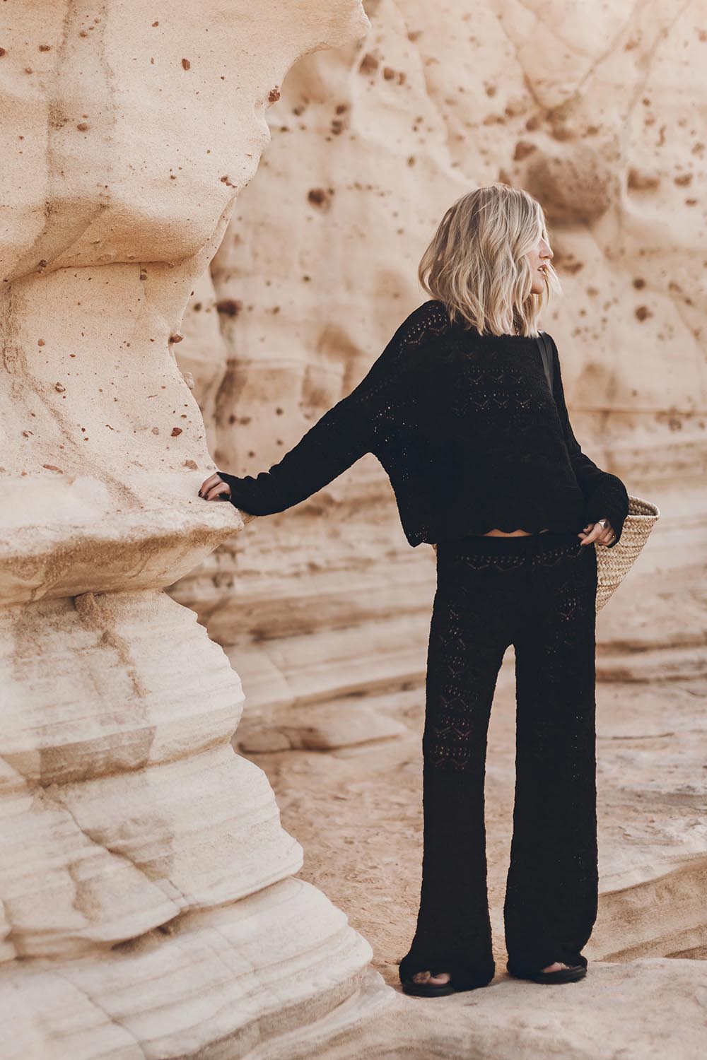 Produit Pantalon en crochet noir en lin et coton Mikuta. Porté avec un pull en crochet noir assorti et des sandales noires.